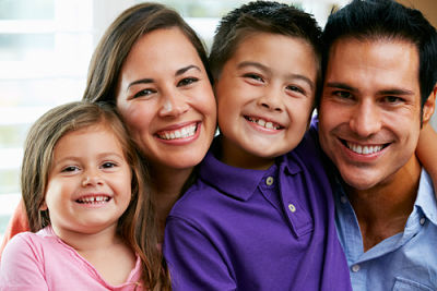 Picture of young hispanic family hugging and smiling.